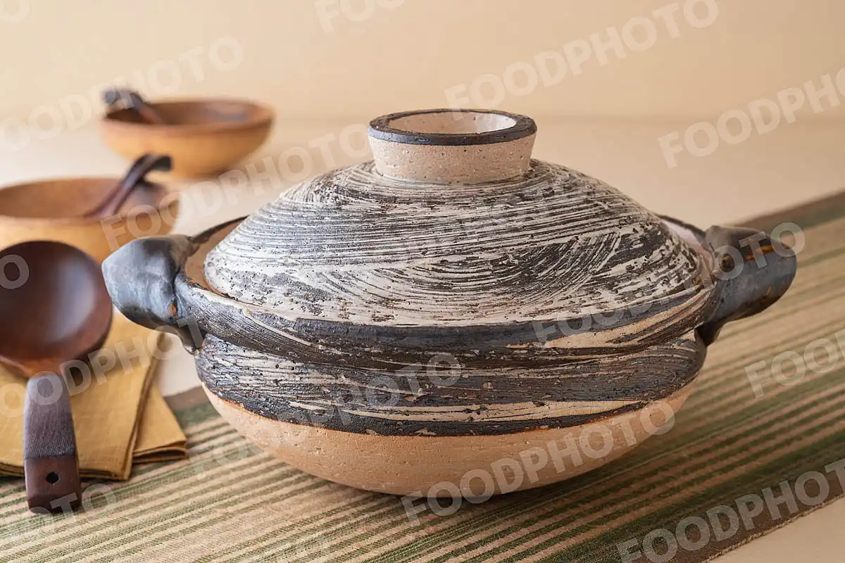 木製のおたまと荒々しい模様の大きな土鍋