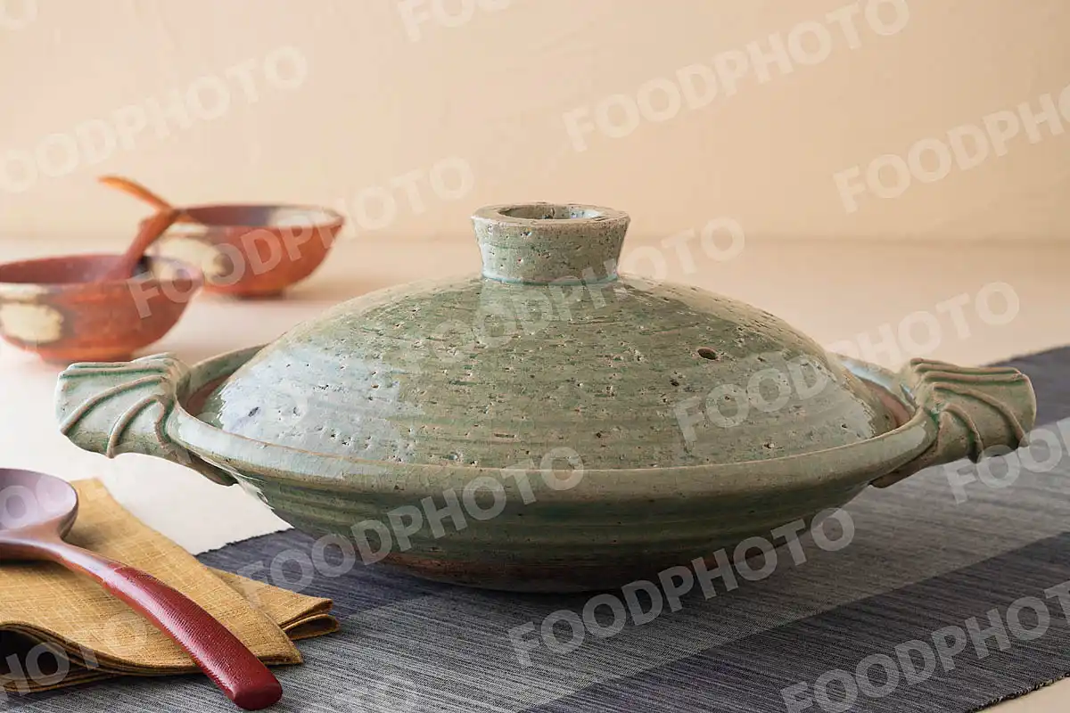 木製のおたまと透明感のある浅緑の土鍋