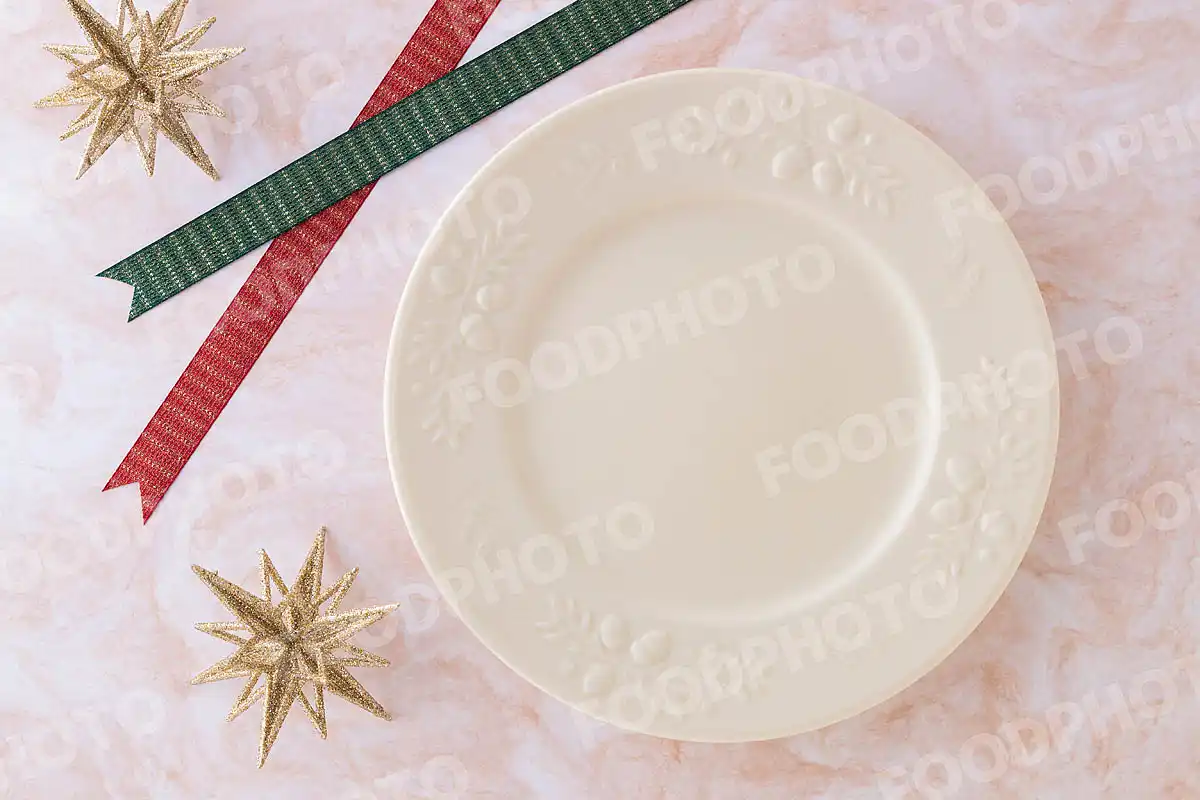 赤緑のリボンとリムに木ノ実を施したクリーム色のラウンドディナープレート