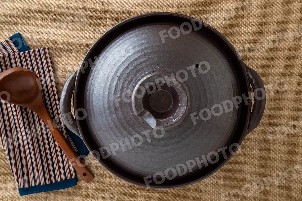 木製のおたまと鋼のような力強い風合いの大きな土鍋 / 蓋閉