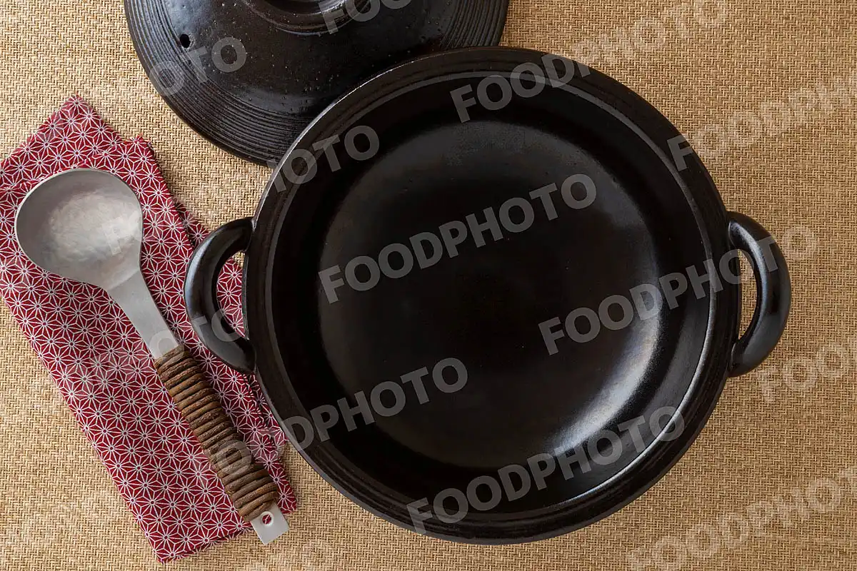 アルミのおたまと光沢感あるシンプルなデザインの黒い土鍋 / 蓋開